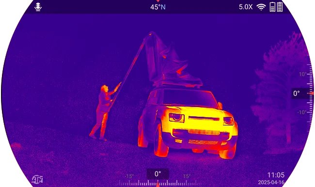 Termisk skærmbillede fra ATN BinoX 6 Dual af en person ved siden af et køretøj om natten med varmesignaturer i en lilla, orange og gul palet samt kompas- og zoomdata på skærmen